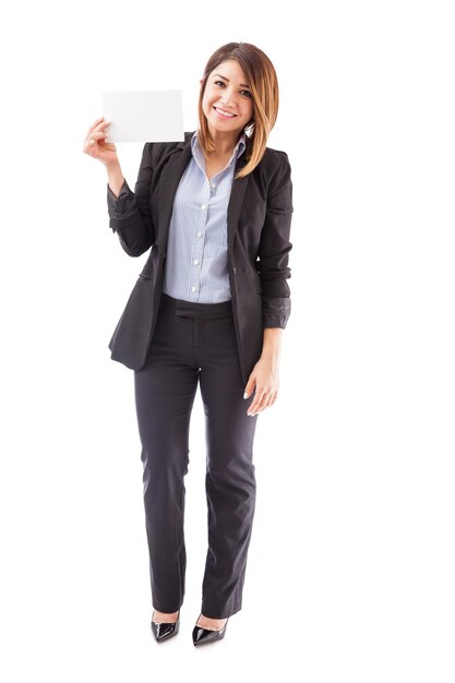 Pretty young salesperson holding up a small sign in her hand and smiling on a white background