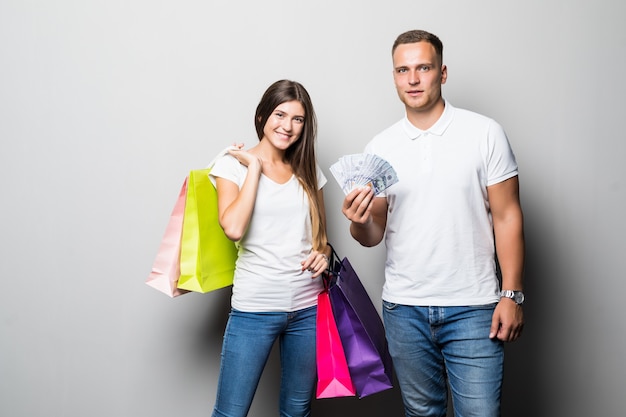 Pretty young smiling sunny student couple holding a lot of coloured shopping bags isolated on white background