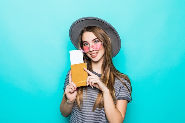 Pretty young teenage lady holds her passport documents with ticket in her hands isolated on green studio wall