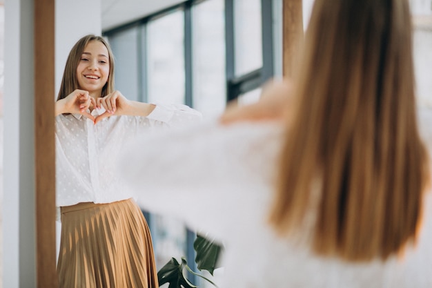 Free photo pretty young woman in casual outfit looking into mirror