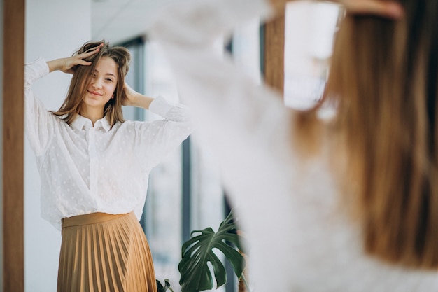 Pretty young woman in casual outfit looking into mirror