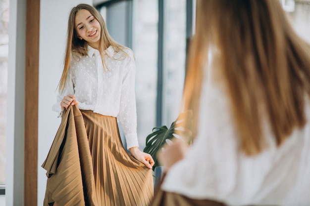 Free photo pretty young woman in casual outfit looking into mirror