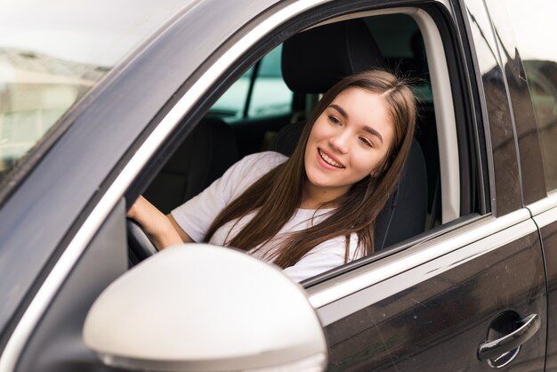 Pretty young woman driving her new car on the road