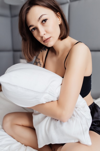 Pretty Young woman embracing her pillow in the morning in her bedroom at home