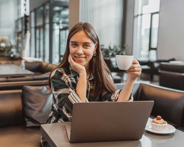 Foto gratuita donna abbastanza giovane che gode di una pausa caffè