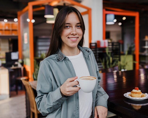 コーヒーカップを楽しんでいるかなり若い女性