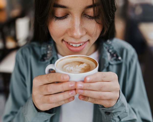 コーヒーカップを楽しんでいるかなり若い女性