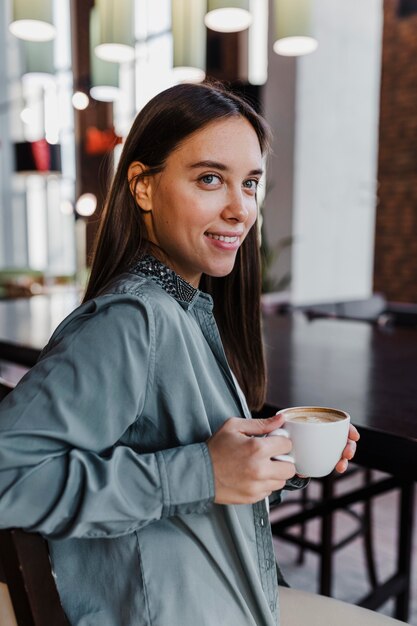 コーヒーカップを楽しんでいるかなり若い女性