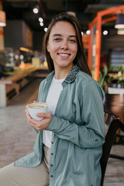 コーヒーカップを楽しんでいるかなり若い女性