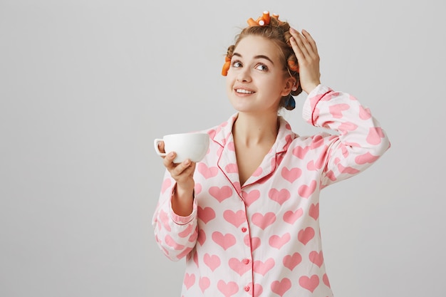 ヘアカーラーとパジャマを着て朝のコーヒーを飲むのはかなり若い女性