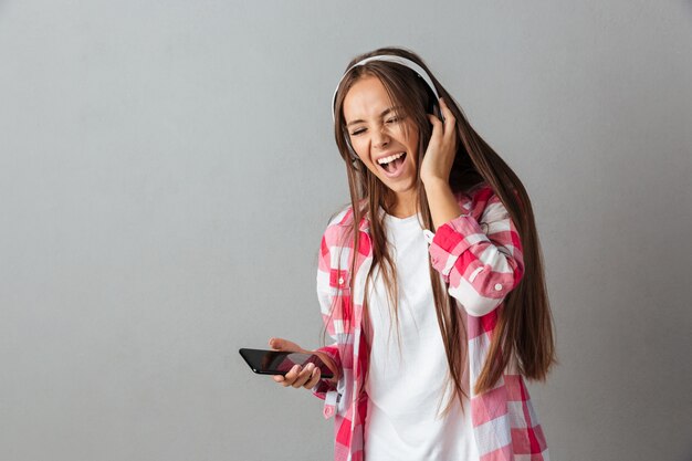 Pretty young woman in headphones listening to music and singing