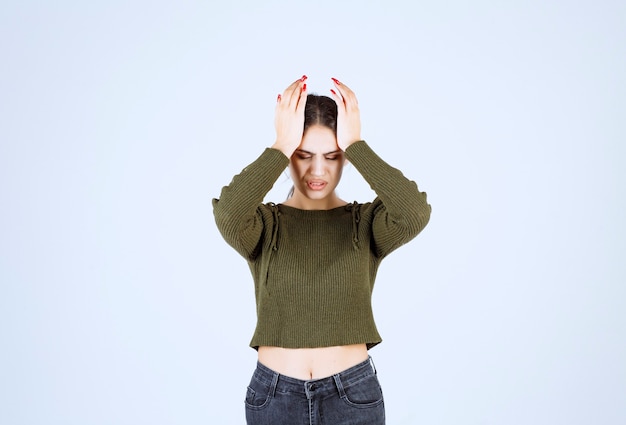 Free photo pretty young woman holding her face on white wall