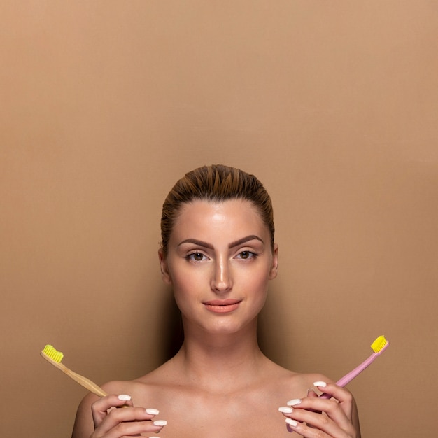 Pretty young woman holding toothbrushes