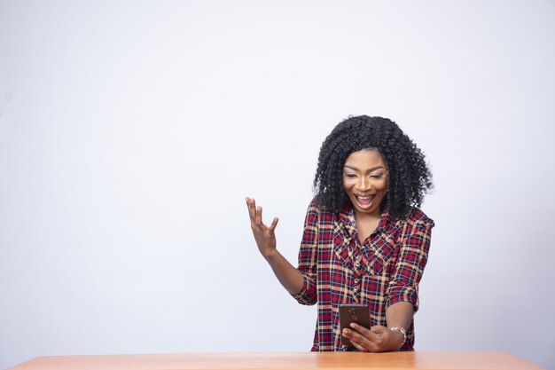 Pretty young woman looking surprised and excited while looking at her phone