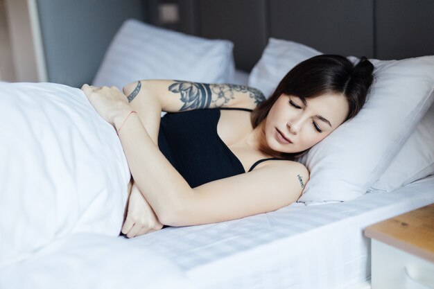 Pretty Young woman lying in bed doesn't want to wake up