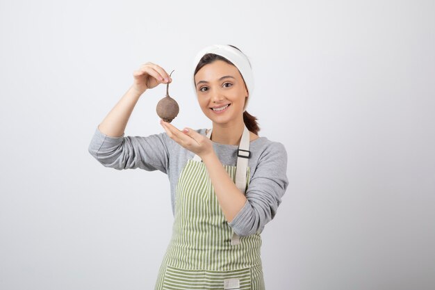 Modello di donna abbastanza giovane in grembiule che tiene una barbabietola.