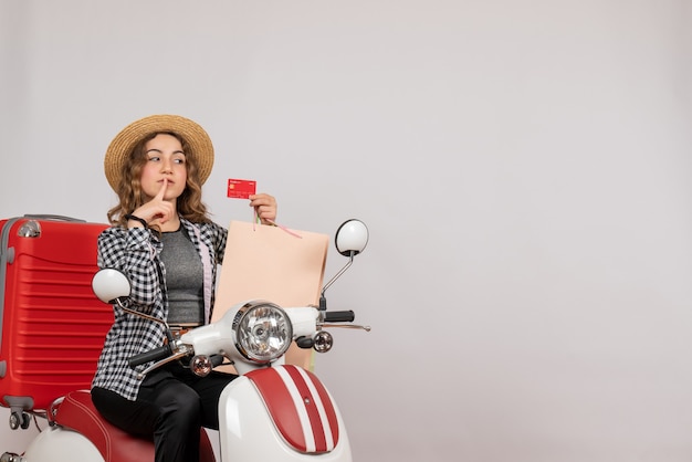 Bella giovane donna sul motorino che tiene la carta su gray