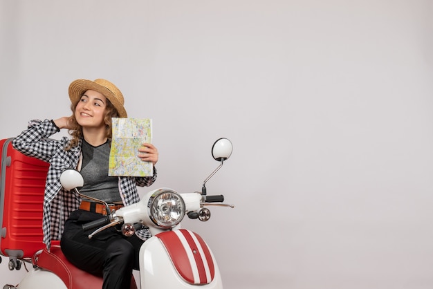 Bella giovane donna sul motorino che tiene mappa su gray