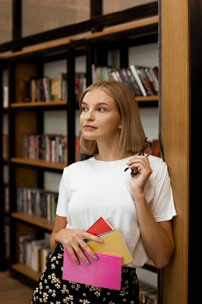 Бесплатное фото Довольно молодая женщина позирует в библиотеке
