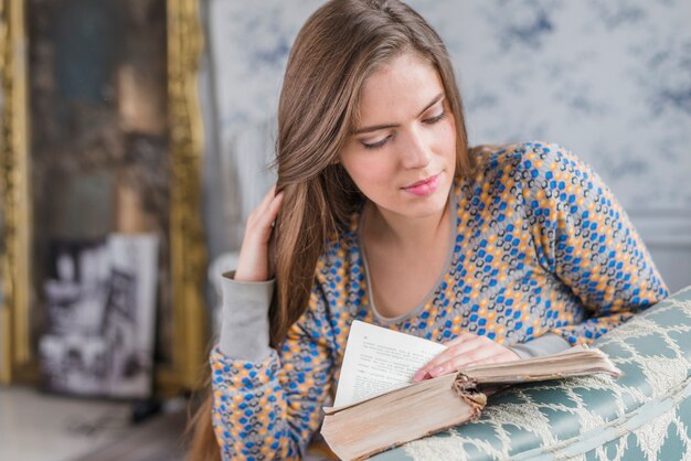 Pretty young woman reading book seriously