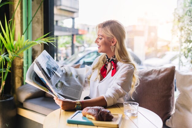 Pretty young woman sitting in caf� reading newspaper