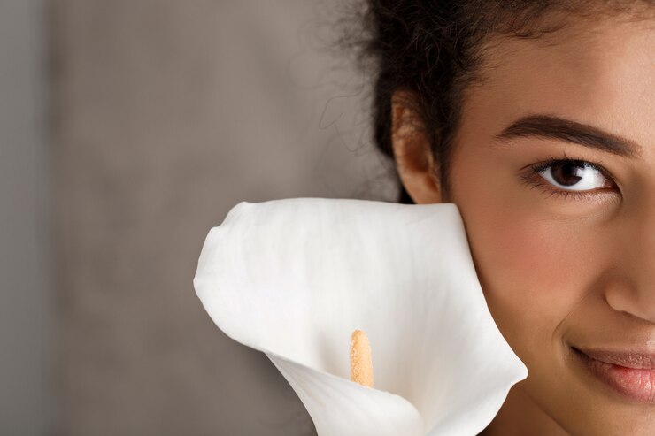 Free Photo pretty young woman smiling, holding white flower over beige wall