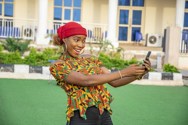 Pretty young woman smiling and using her mobile phone outdoors