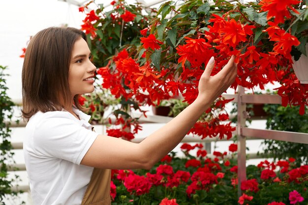 Довольно молодая женщина нюхает красивые красные цветы