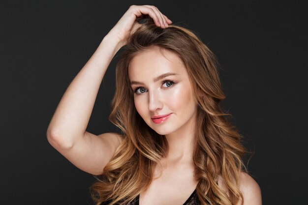 Pretty young woman standing over grey wall