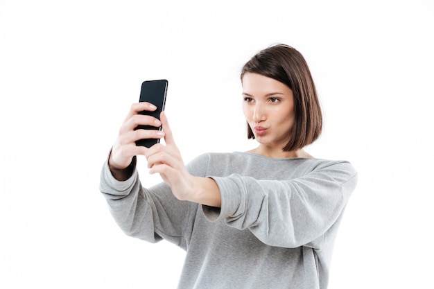 Pretty young woman taking selfie on mobile phone