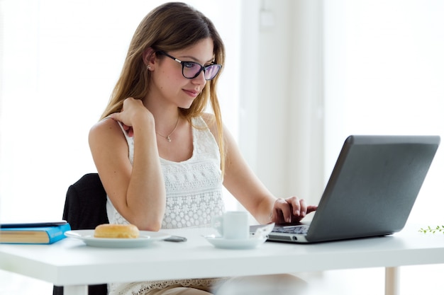 Pretty young woman using her laptop at home.