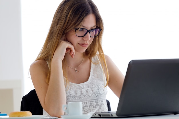 Pretty young woman using her laptop at home.