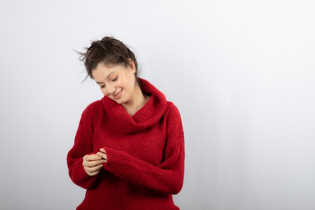 Довольно молодая женщина в теплый красный свитер позирует.