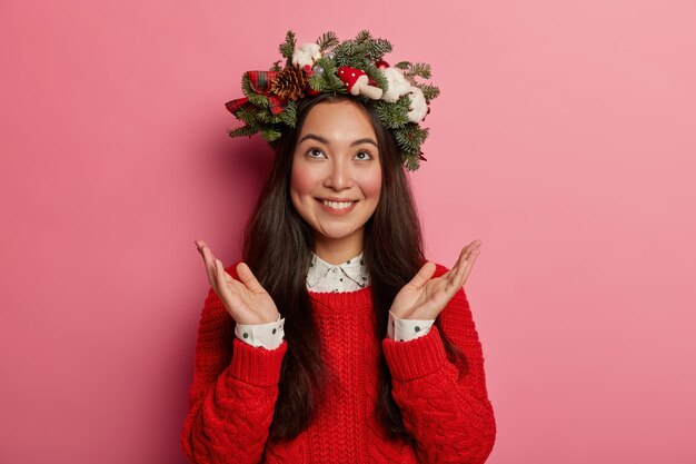 Pretty and young woman wearing Christmas wreath on her head