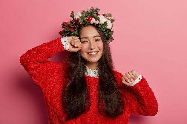 Pretty and young woman wearing Christmas wreath on her head