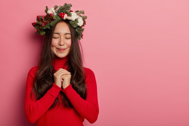 Pretty and young woman wearing Christmas wreath on her head