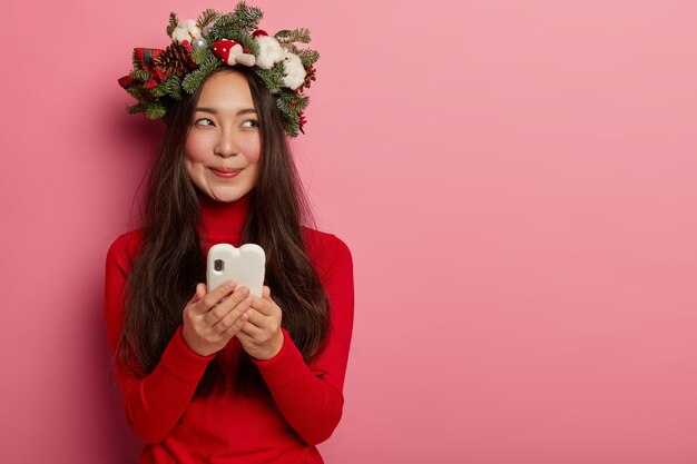 彼女の頭にクリスマスリースを着ているきれいで若い女性