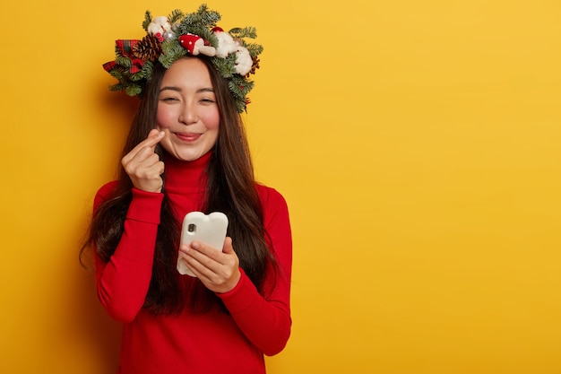 Pretty and young woman wearing Christmas wreath on her head