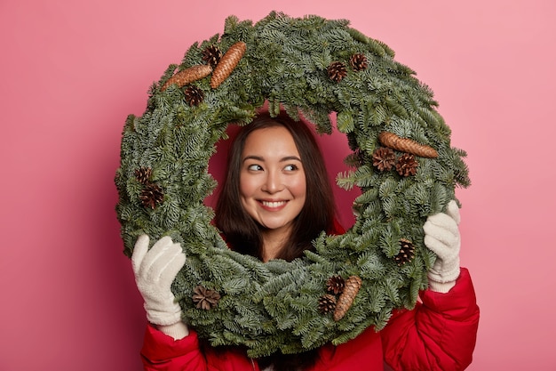 彼女の頭にクリスマスリースを着ているきれいで若い女性