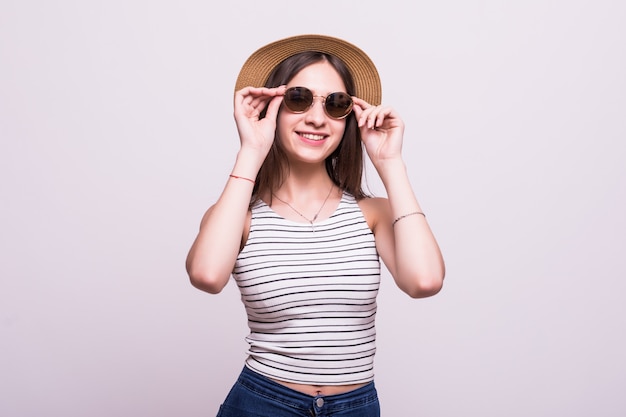 Pretty young woman wearing a hat, sunglasses isolated over white background