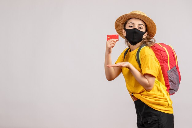 pretty young woman with backpack holding up card on grey