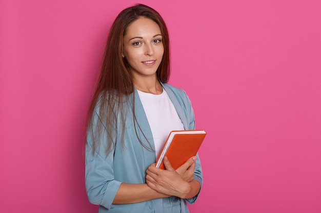 メモ帳の手に立っている暗いストレートの髪を持つかなり若い女性