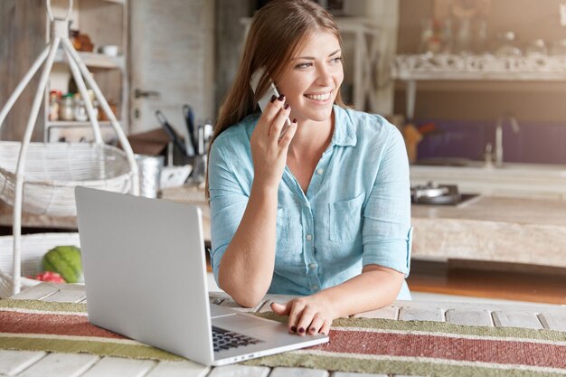 Pretty young woman with long hair sitting in cafe with laptop