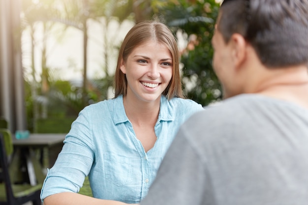 Pretty young woman with long hair sitting in cafe with man