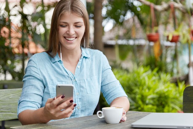 Pretty young woman with long hair sitting in cafe with phone