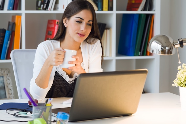 Pretty young woman working with laptop in her office.