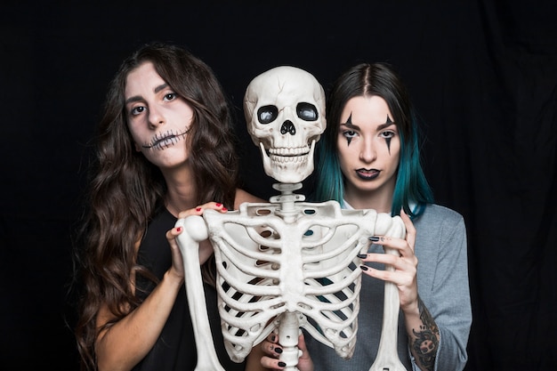 Free photo pretty young women with plastic skeleton