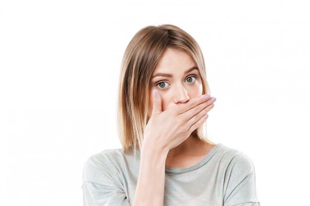 Pretty young young woman covering her mouth with hand