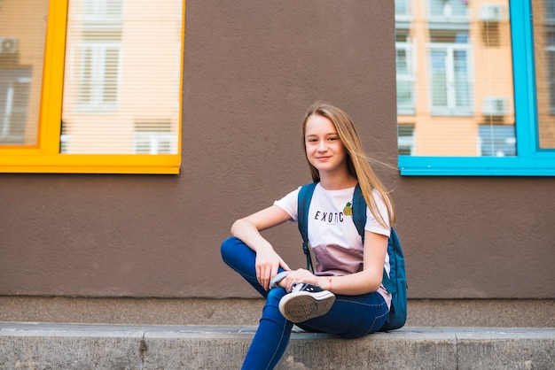 Pretty youngster with backpack posing outside