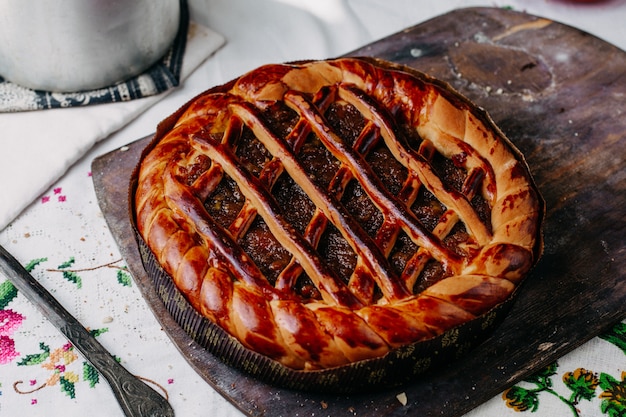 Foto gratuita ciambellina salata formata con tondo al cioccolato tostato dolce gustoso marrone all'interno teglia rotonda sulla scrivania in legno marrone